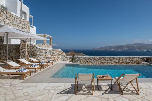 une piscine dans une villa avec des chaises et une piscine dans l'établissement Mykonos Esti Luxury Villas, à Agios Ioannis Mykonos