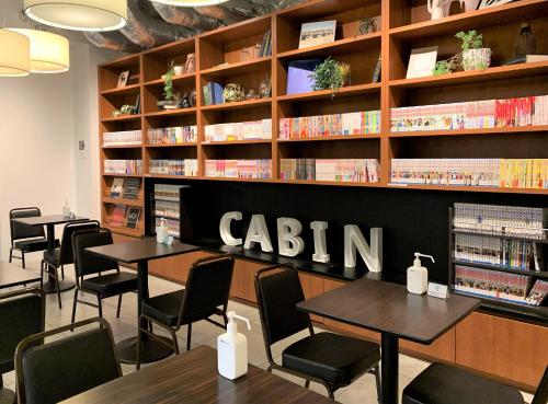 First Cabin Ichigaya في طوكيو: مكتبة بها طاولات وكراسي ورفوف كتب