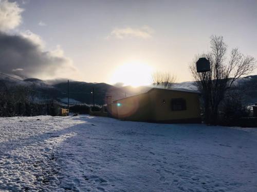 un campo coperto di neve con il sole che tramonta dietro un edificio di Casa tafi a Tafí del Valle