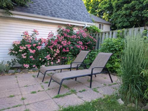 dois bancos sentados ao lado de uma cerca com flores cor-de-rosa em Garden 2 Storey House em Cataratas do Niágara