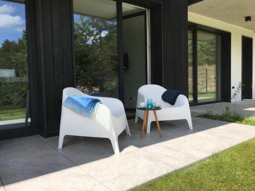 two white chairs and a table on a patio at Apartament 23 w Porto Łeba in Łeba