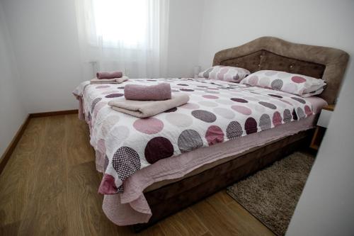 Schlafzimmer mit einem Bett mit einer Polka-Punktdecke und Kissen in der Unterkunft Apartman Minja in Subotica