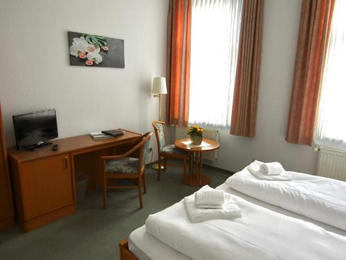 um quarto de hotel com duas camas e uma secretária em Pension Hexenkessel em Wernigerode