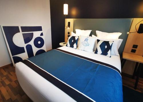 een slaapkamer met een blauw en wit bed met kussens bij Residhome Asnieres in Asnières-sur-Seine