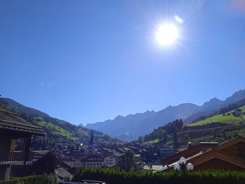 a view of a village with the sun in the sky at Hotel les Sapins in La Clusaz