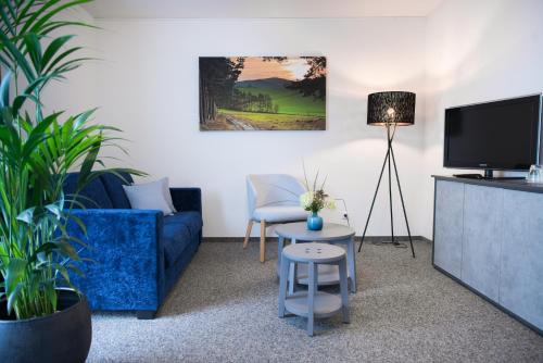 sala de estar con sofá azul y TV en Aktivhotel Inselsberg, en Tabarz