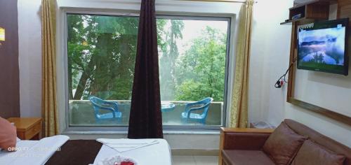 a living room with a large window and a television at Hotel Al Azeem in Ayubia