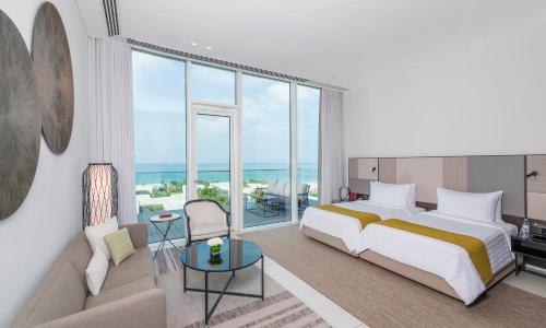 a bedroom with a king sized bed and a couch at The Oberoi Beach Resort, Al Zorah in Ajman 