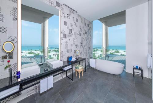 a bathroom with a tub and a large window at The Oberoi Beach Resort, Al Zorah in Ajman 