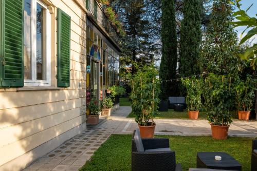 een gebouw met groene luiken en stoelen op een tuin bij Villa Romantica Wellness & SPA in Lucca