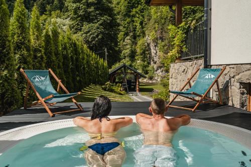 dos personas sentadas en un jacuzzi en una piscina en Apartamenty Magia Gór, en Szczawnica