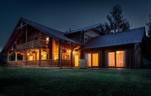 Une grande maison en bois éclairée la nuit dans l'établissement Tatranský Zrub, à Nová Lesná