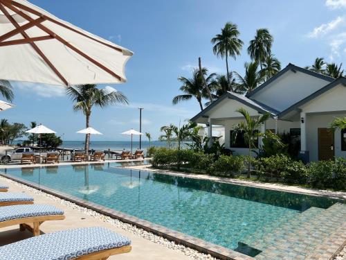 uma piscina num resort com cadeiras e guarda-sóis em Pearl of Samui Resort em Lamai