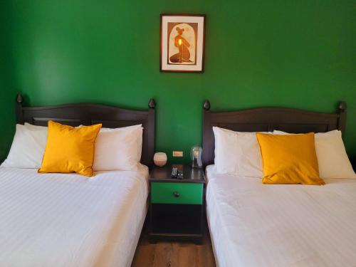 um quarto verde com duas camas com almofadas amarelas em Motel Abricafé em Stoneham