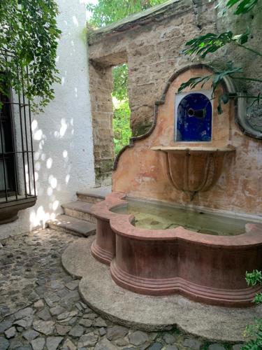 a water fountain in a yard with a stone wall at Posada El Antaño in Antigua Guatemala