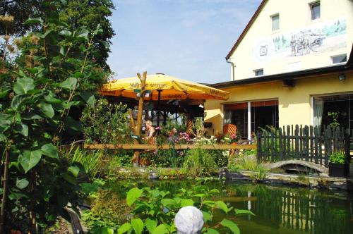 a garden with a pond in front of a house at Landhotel Heidekrug in Dohma