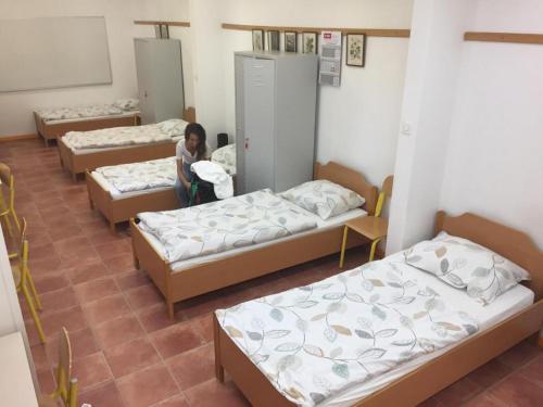 una donna seduta in una stanza con tre letti di Youth Hostel Proteus Postojna a Postumia