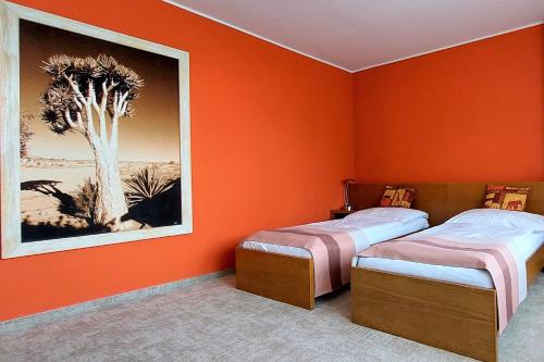 two beds in a room with an orange wall at Afrika Hotel Frýdek-Místek in Frýdek-Místek