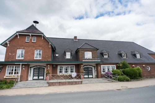 duży dom z czerwonej cegły z czarnym dachem w obiekcie Landhaus Hamester - Hotel & Restaurant w mieście Basthorst