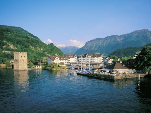 una piccola cittadina su un fiume con montagne sullo sfondo di Hotel Winkelried am See a Stansstad