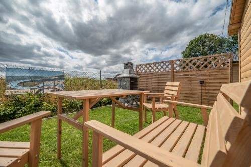 einen Holztisch und Stühle auf einer Terrasse mit Spielplatz in der Unterkunft Osada Trzy Siostry in Pobierowo