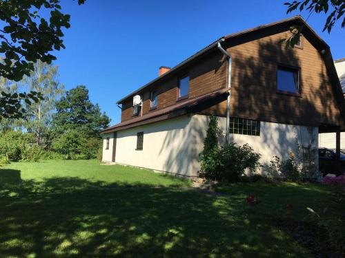 una casa con techo de gambrel en un patio verde en Lotes apartamenti, en Kuldīga