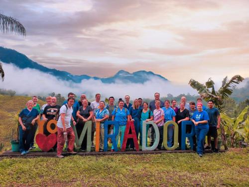 a group of people posing for a picture with a sign at El Mirador de Tansu in Lanquín