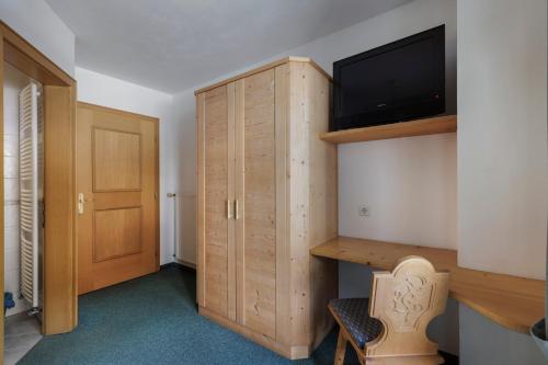 a room with a tv and a wooden cabinet at Garni Ziernheld in Malles Venosta