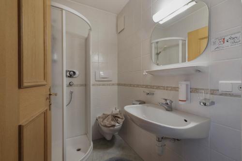 a white bathroom with a sink and a toilet at Garni Ziernheld in Malles Venosta