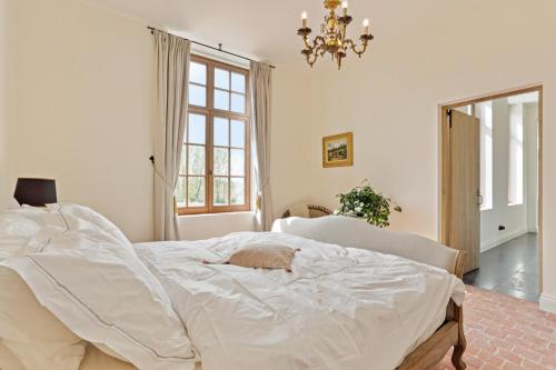 a bedroom with a white bed with a cat laying on it at Huis Potaerde, luxe villa, vakantiewoning - landhuis nabij Brussel in Merchtem