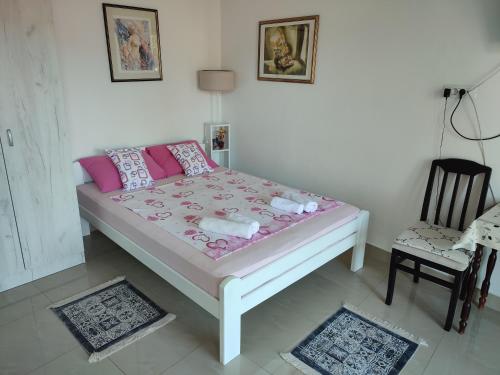 Un dormitorio con una cama con almohadas rosas y una silla en Smestaj Vella, en Herceg-Novi