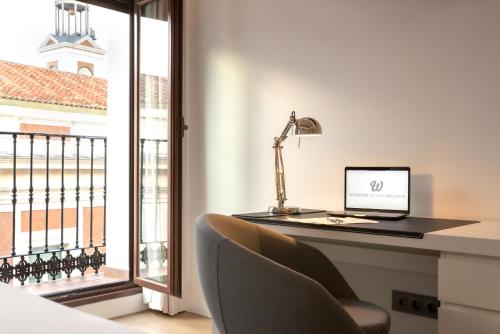 einen Schreibtisch mit Laptop neben einem Fenster in der Unterkunft Woohoo Rooms Boutique Sol in Madrid