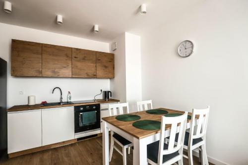 a kitchen with a table and a clock on the wall at Nowy w centrum in Giżycko