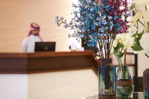 een bar met vazen met blauwe en witte bloemen bij Diwan Residence Hotel- ِAlnaeem in Jeddah