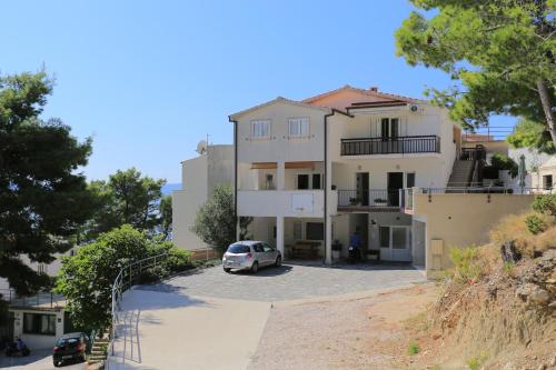 une maison blanche avec une voiture garée dans un parking dans l'établissement Apartments by the sea Brela, Makarska - 6688, à Brela