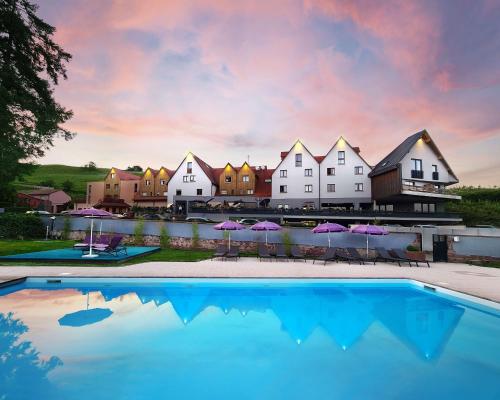 una piscina con sedie e ombrelloni di fronte a un resort di Best Western Hotel & SPA Le Schoenenbourg - Riquewihr - Proche Colmar a Riquewihr