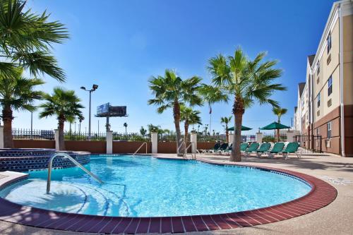 een zwembad met palmbomen en een gebouw bij Candlewood Suites Galveston, an IHG Hotel in Galveston