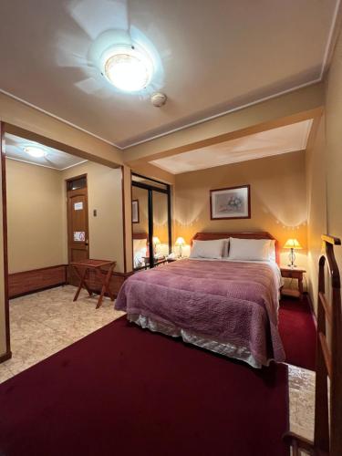 een slaapkamer met een groot bed en een paarse deken bij Hotel Mosul in Concepción