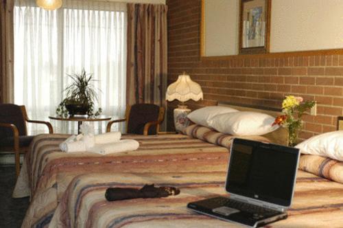 een hotelkamer met 2 bedden en een laptop op het bed bij Motel Du Chevalier in Gatineau