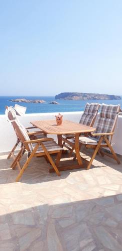 - une table en bois et deux chaises installées à côté de l'océan dans l'établissement Sophia & Chris Studios, à Santa Maria