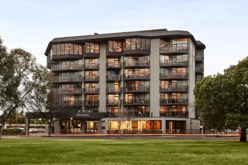 un grand bâtiment avec de nombreuses fenêtres et une pelouse dans l'établissement Rydges South Park Adelaide, à Adélaïde