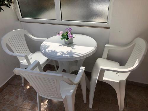 a white table and chairs with a vase of flowers on it at Castello Apartments in Ulcinj