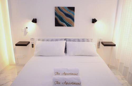 a bedroom with a white bed with a painting on the wall at The Apartment in Porto Santo Stefano