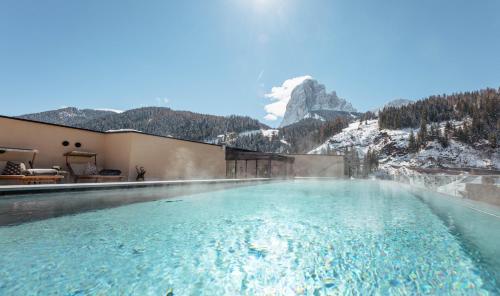 una piscina con una montagna sullo sfondo di Hotel Touring Dolomites a Santa Cristina in Val Gardena