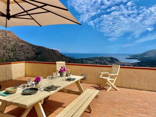 a table and chairs on a patio with an umbrella at Aria di Collina - Isola d'Elba in Porto Azzurro