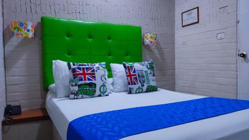 een slaapkamer met een bed met een groen hoofdeinde bij Casa Boston Inn in Barranquilla