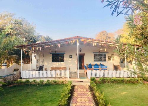 une maison blanche avec une clôture blanche et une cour dans l'établissement West Valley Farm Villa, à Lavasa