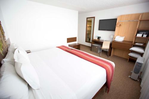 a hotel room with a white bed and a desk at Tierra Viva Puno Plaza in Puno