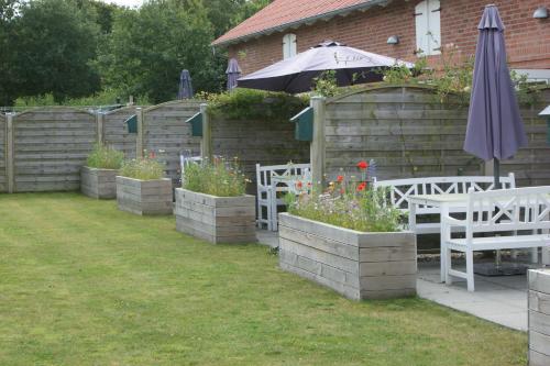 un giardino con tavolo, sedie e ombrellone di Lustrup Farmhouse a Ribe