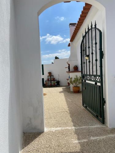 een deur naar een wit huis met een groene poort bij Casa do Canto - Uma casa no campo, perto da praia. in Óbidos